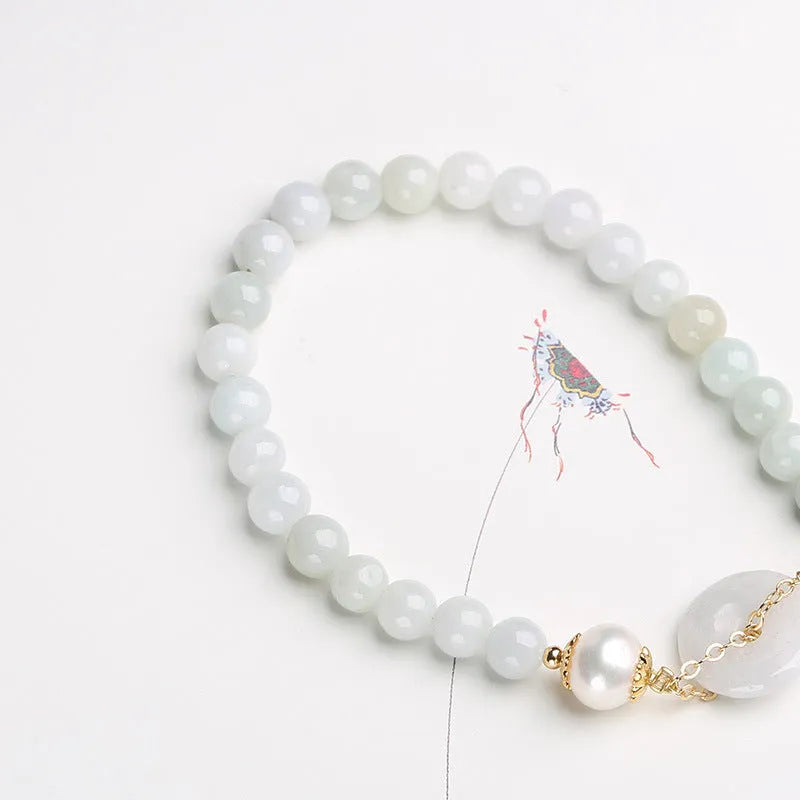 Close-up of a green jade and pearl bracelet with a geometric peace buckle on an elastic band.