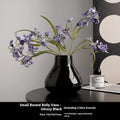 Ceramic round belly vase with coloured glaze finish in black or white, shown with artificial orchid stems