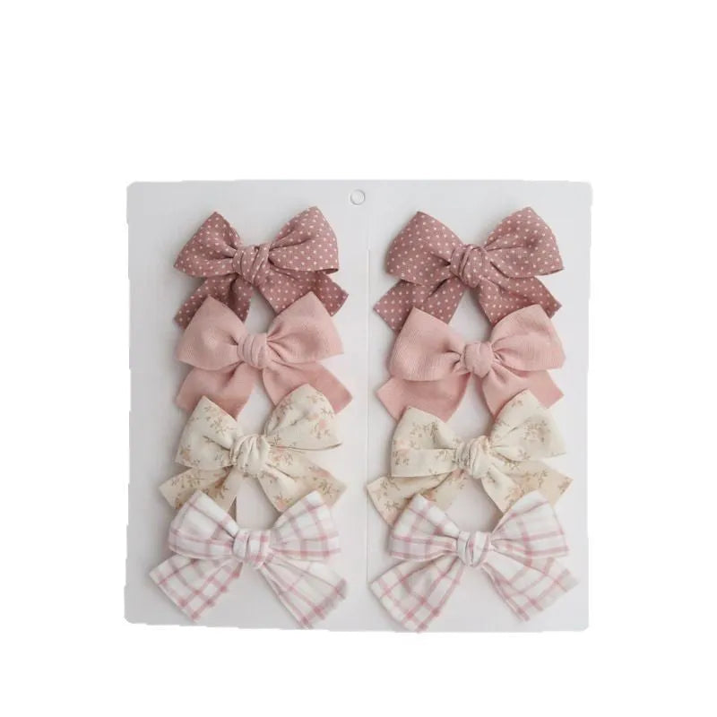 Set of children's fabric hairclips with dovetail bows in eight different colours and patterns.