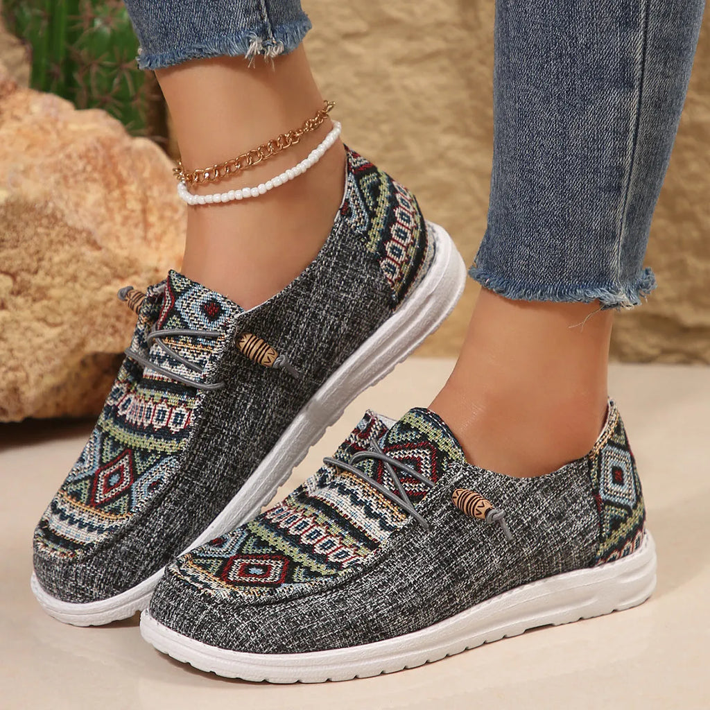 Women's black flat slip-on shoes with round toe and rubber sole on a neutral background.