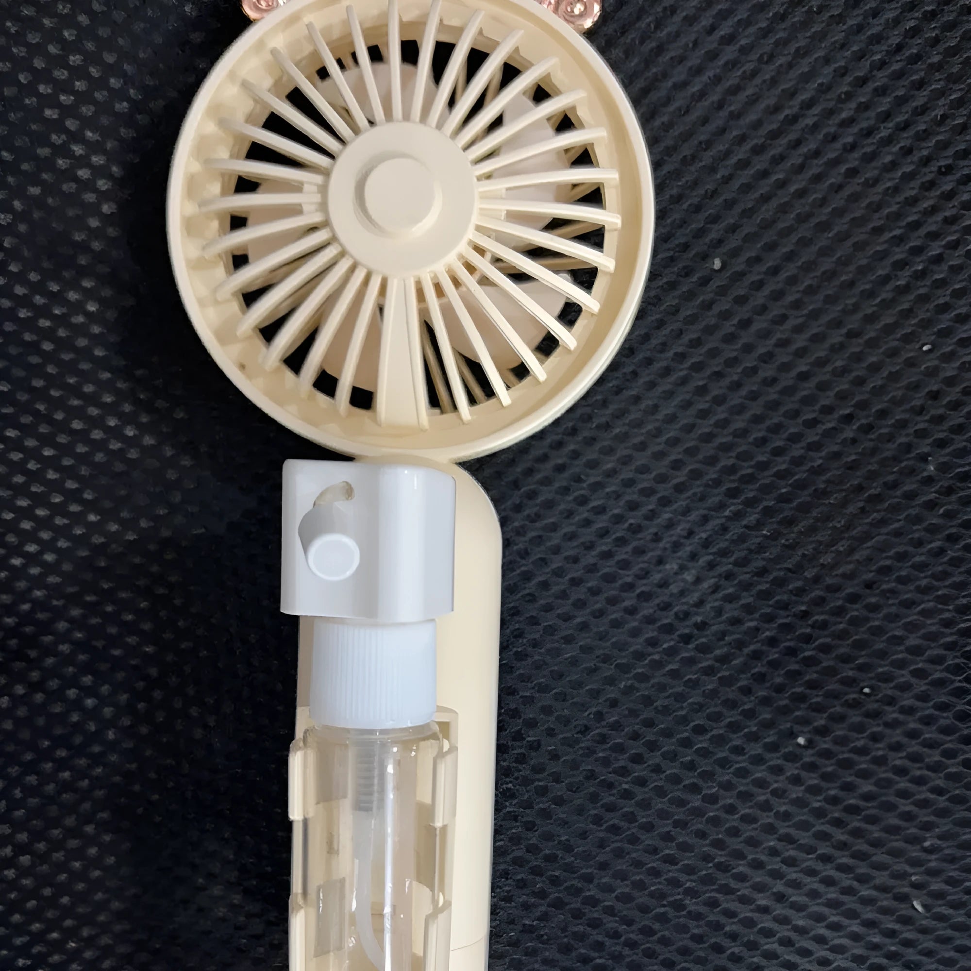 USB rechargeable plastic personal fan in apricot colour on a white background.