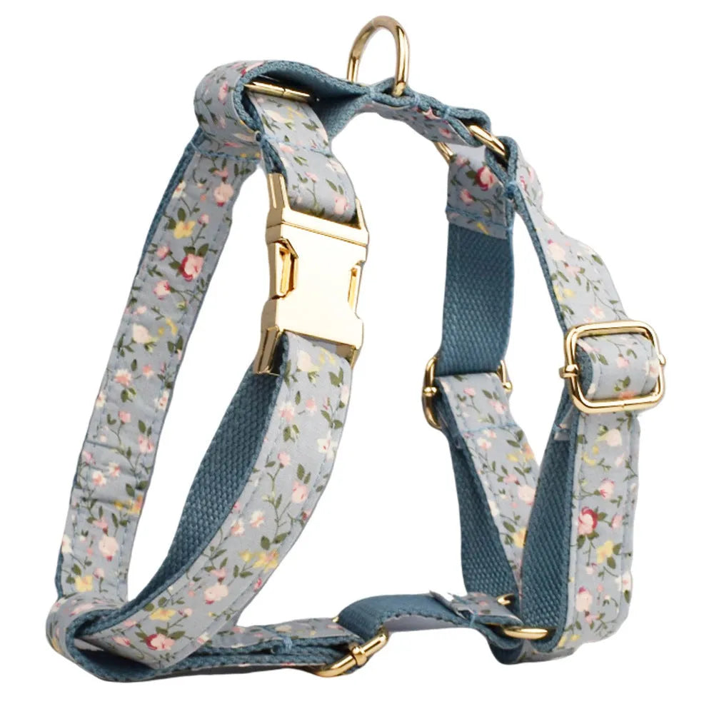 Blue floral patterned dog collar and matching leash, vest, and bow set on a white background.