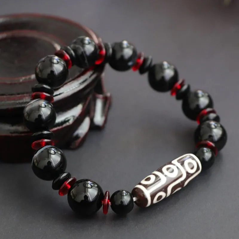 Black agate Dzi bead bracelet with hand-woven construction and geometry beads.
