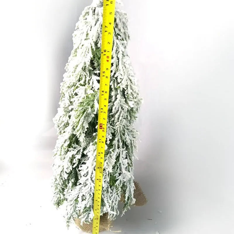 Small 24-inch artificial Christmas tree with snow sprayer finish and integrated lights on desktop