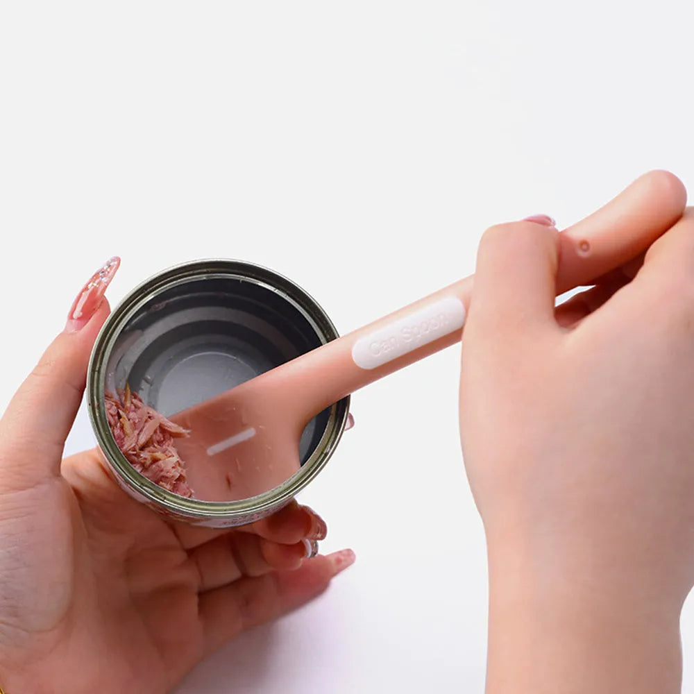 Long green handled pet food scoop next to a dog food tin, showing its right-angle scraping head.