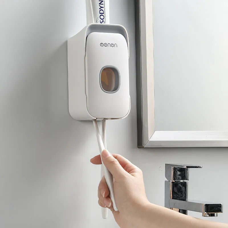 Blue automatic toothpaste dispenser mounted on a bathroom wall with a toothbrush below.