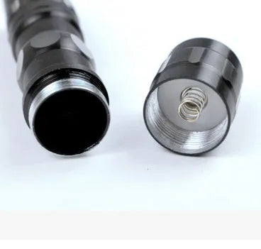 Small black aluminium alloy LED mini flashlight showing scale next to a AA battery.