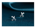 A pair of silver ear nail earrings with a mini scissors screw design and screw-back closures.