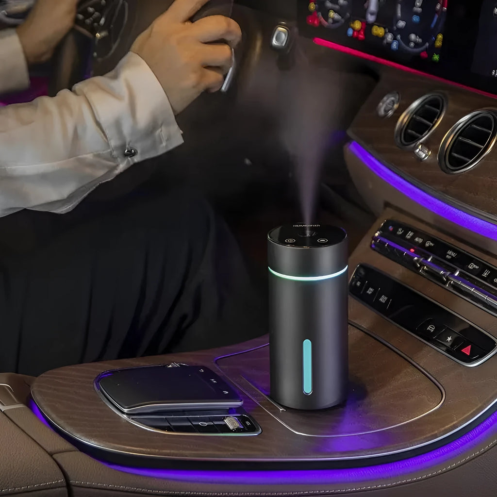 Black aluminium car humidifier and essential oil diffuser with night light on a desk next to USB cable.