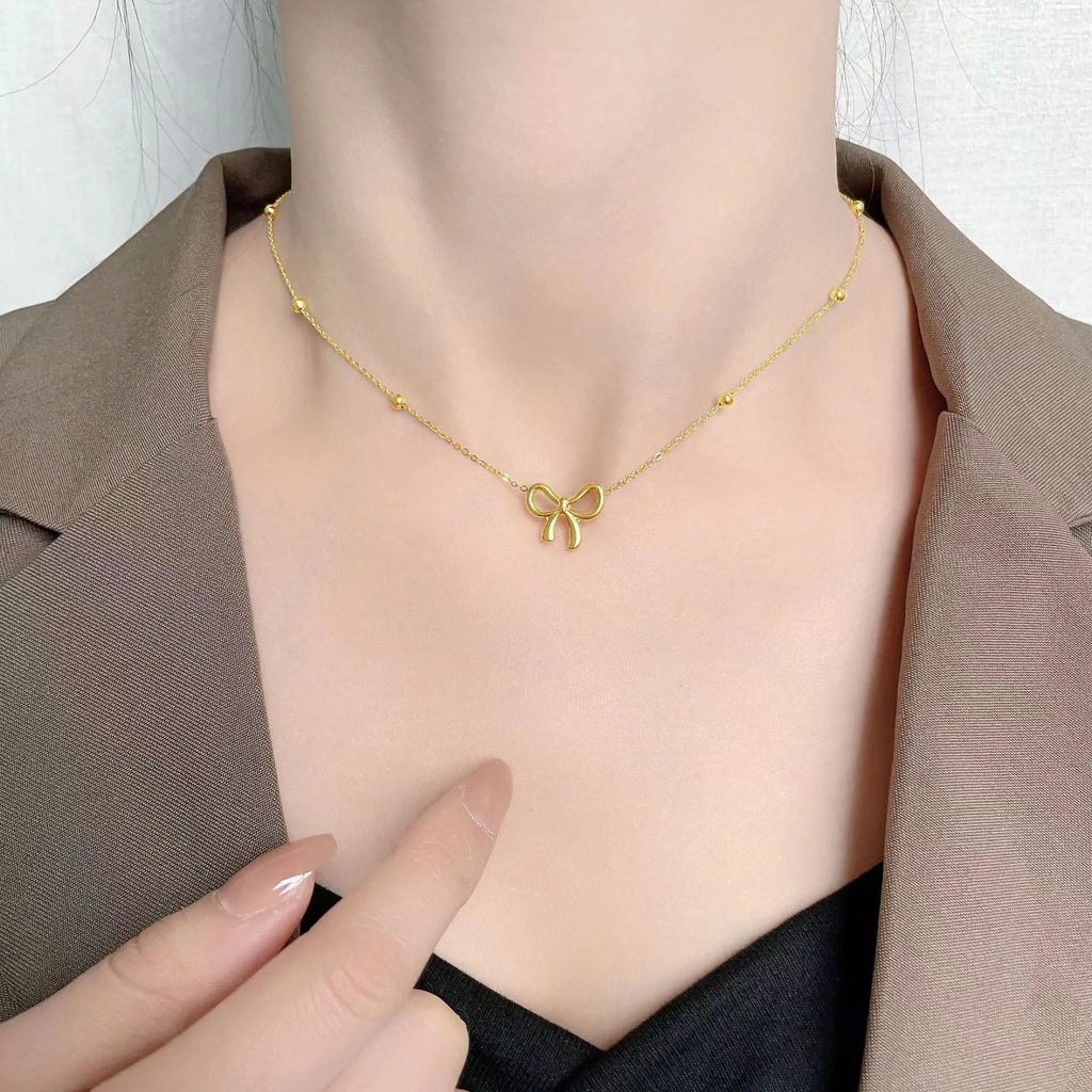Gold bow necklace with adjustable cross chain on women's neck