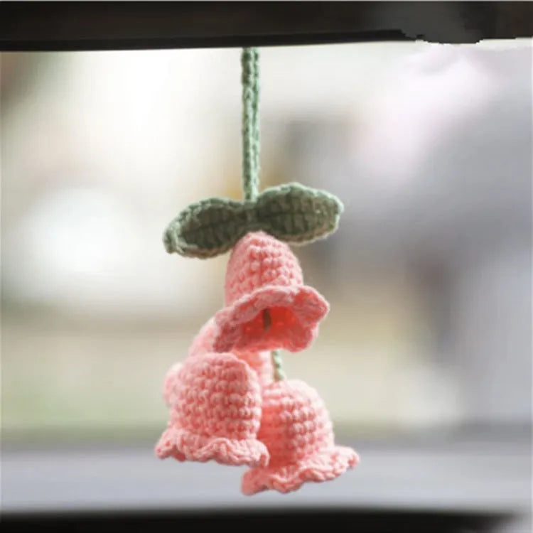 Green and white knitted wool car plant decoration hanging from a rope.