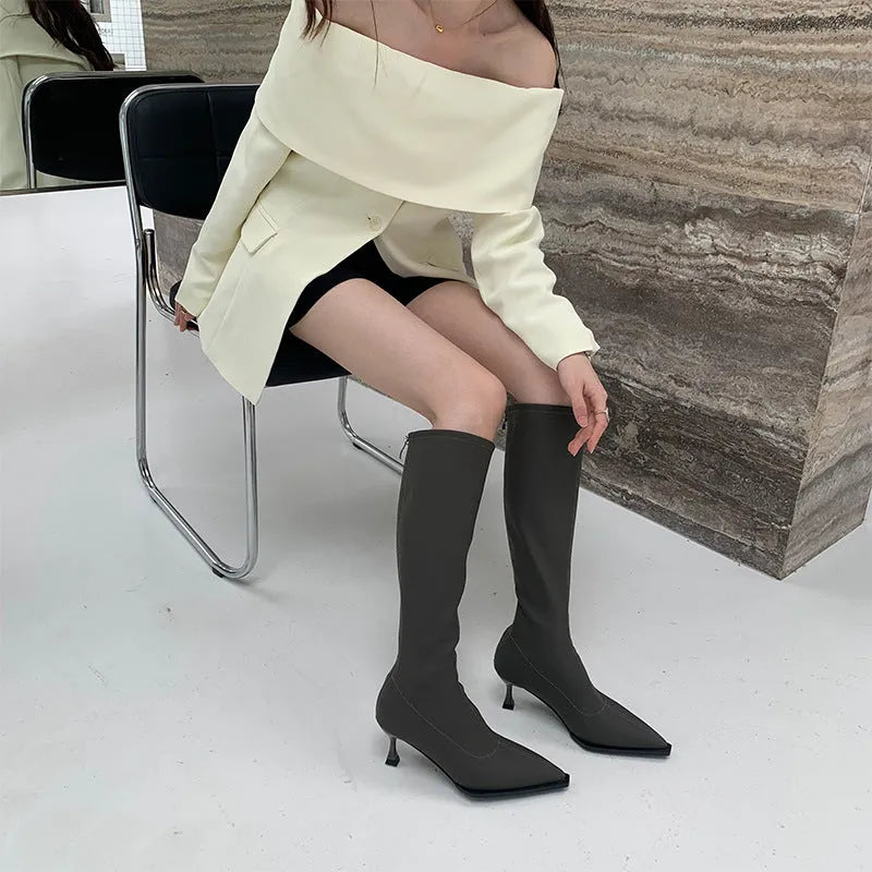 Black women's pointed toe below-knee boots with stiletto heel and back zipper on a white background.