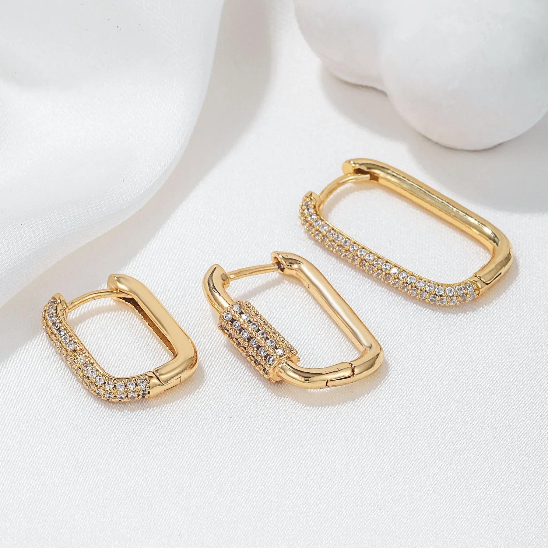 Three geometric ear clips with micro-inlaid zircon stones on copper, showing gold and white gold colour options