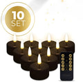 Set of four black flameless LED tealight candles showing flickering warm white glow.