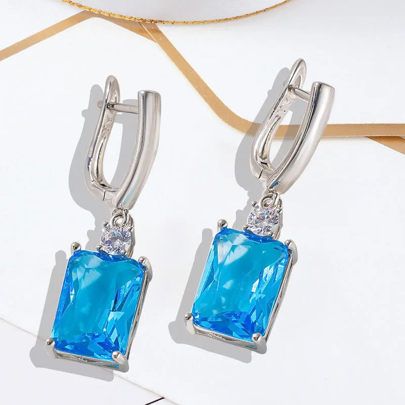 A pair of square-shaped gold and silver electroplated copper earrings on a flat surface.