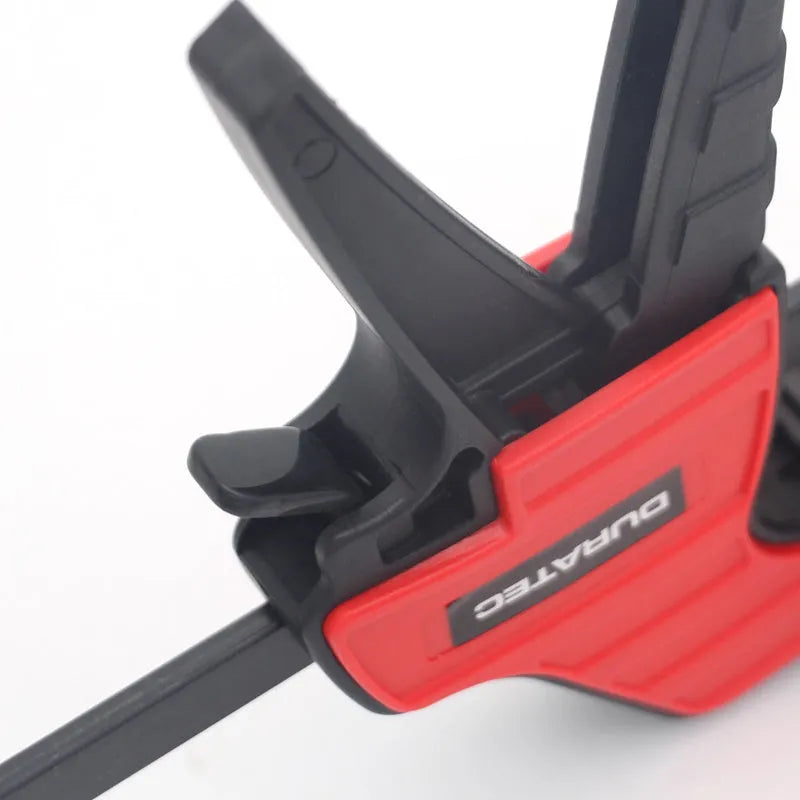 Black plastic woodworking clamp with quick-adjust key and soft rubber protective grip.