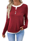 Women's black fake two-piece round neck button pullover sweater with long sleeves on a hanger.