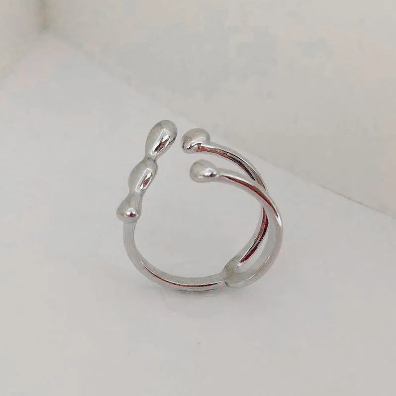 Open circle brass fashion ring with spherical beads in gold tone on a hand.