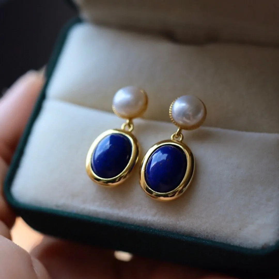 A pair of simple sterling silver stud earrings with blue lapis lazuli pearls and auspicious pattern details.
