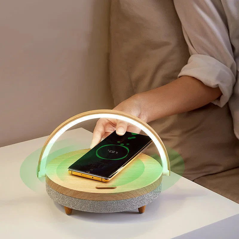 Wireless charging LED night light with Bluetooth speaker in marble pattern finish on a wooden table.