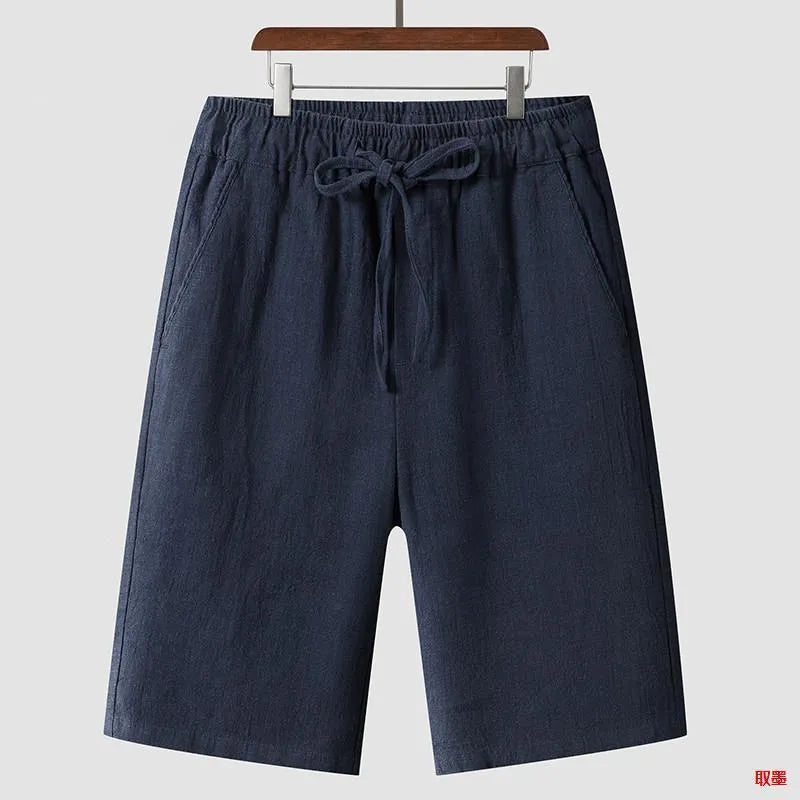 Men's beige linen casual shorts with loose cropped fit and elastic waistband on a neutral background.