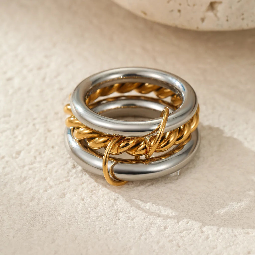 Stacked stainless steel rings with 18K gold plating in exaggerated design on woman's hand