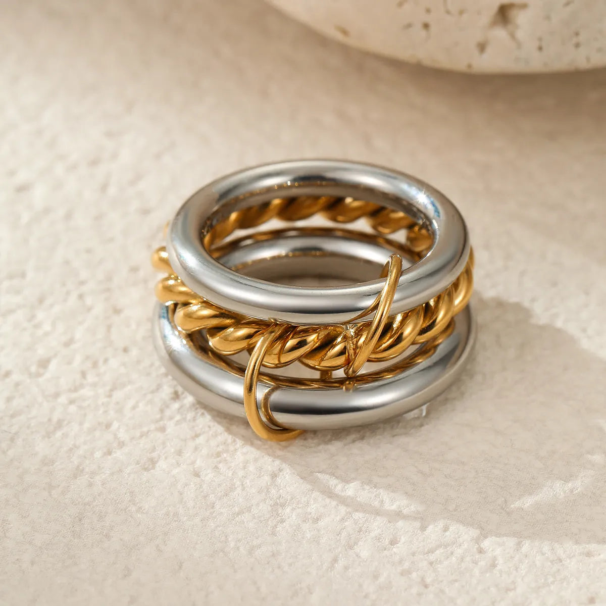 Stacked stainless steel rings with 18K gold plating in exaggerated design on woman's hand