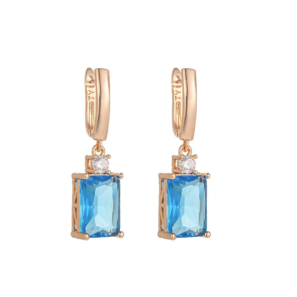 A pair of square-shaped gold and silver electroplated copper earrings on a flat surface.