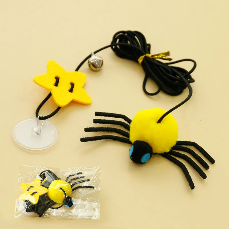 Red hanging cat toy with feather wand, bells, and spider on elastic rope, mounted on a door.