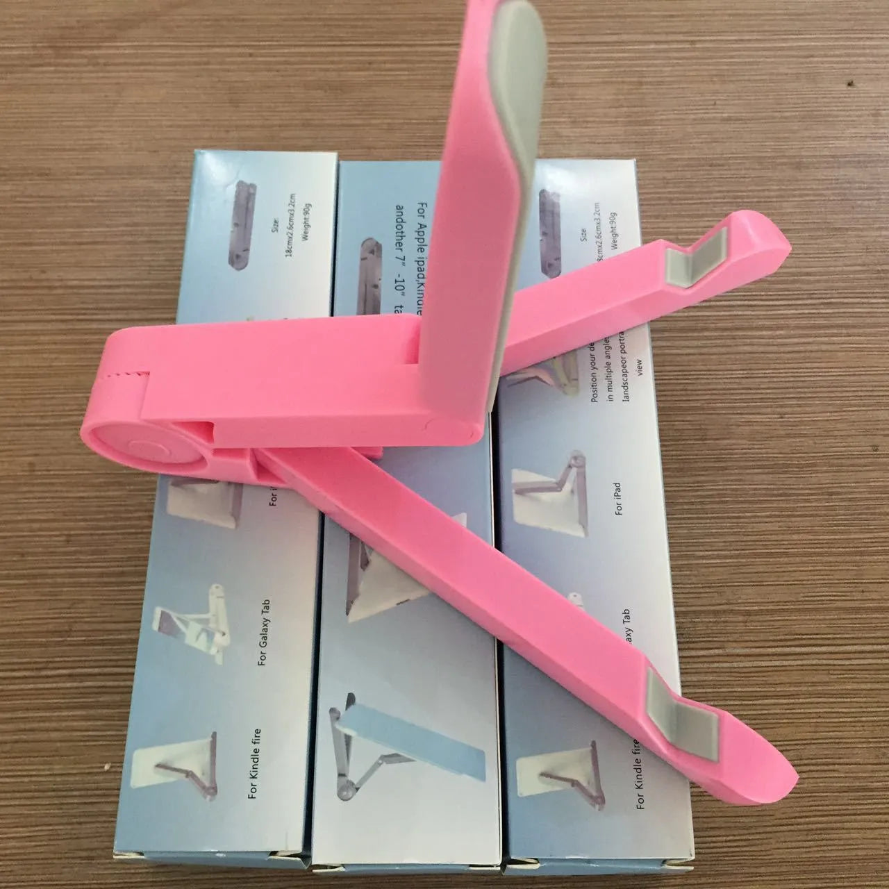 Black foldable aluminium tablet holder showing adjustable stand in open and closed positions on a desk.