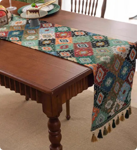 Long decorative table runner with handwoven tassels in a blue ginkgo leaf pattern on a wooden table.