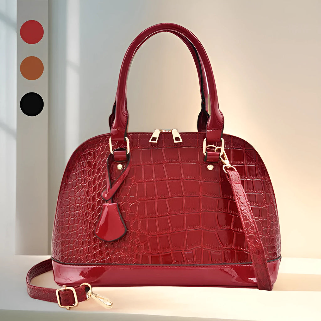 Large shiny black PU leather crossbody bag showing structured shell shape and shoulder strap.