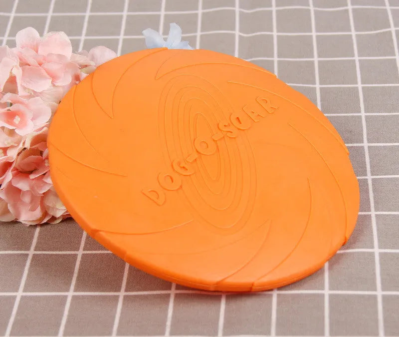 Dog training set with plastic frisbee and bite ring in orange and green colours on grass
