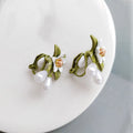 Close-up of women's camellia flower ear clip earrings with sterling silver needle accents on a contrasting background.