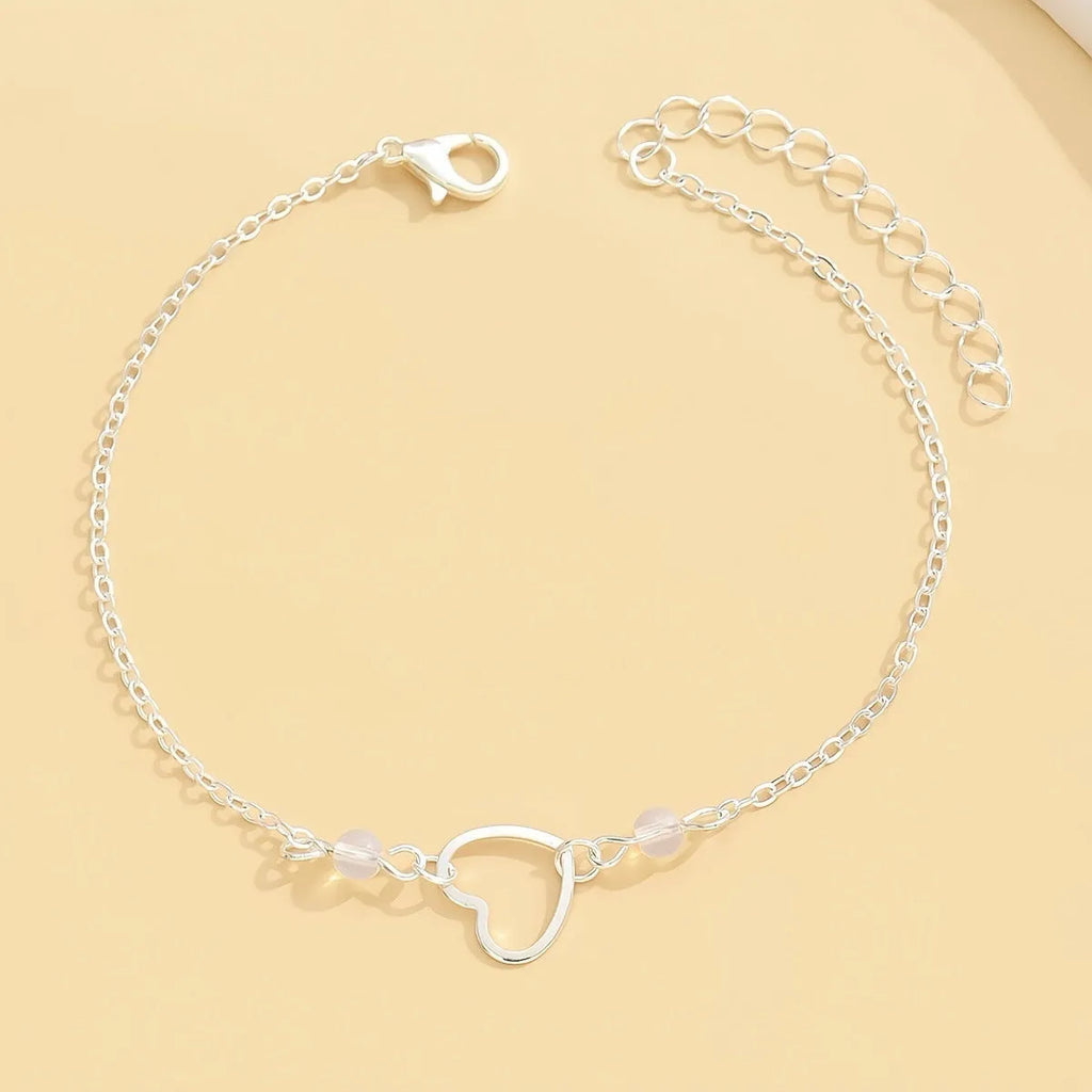 Adjustable gold or silver alloy anklet with a simple heart-shaped pendant.