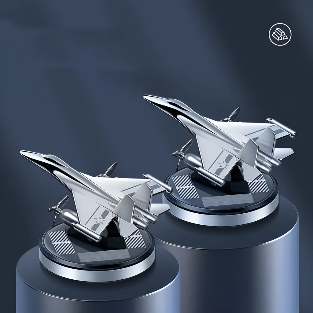 Silver solar powered rotating fighter plane air freshener ornament on a car dashboard.