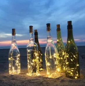 Copper wire LED string light with bottle stopper illuminated in a glass wine bottle.