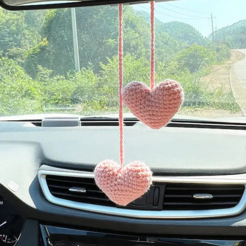 Green and white knitted wool car plant decoration hanging from a rope.