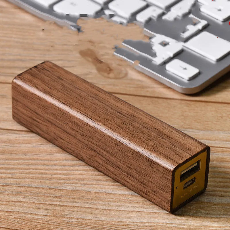 Black walnut wood portable power bank showing natural grain, with dimensions 100mm by 25mm.