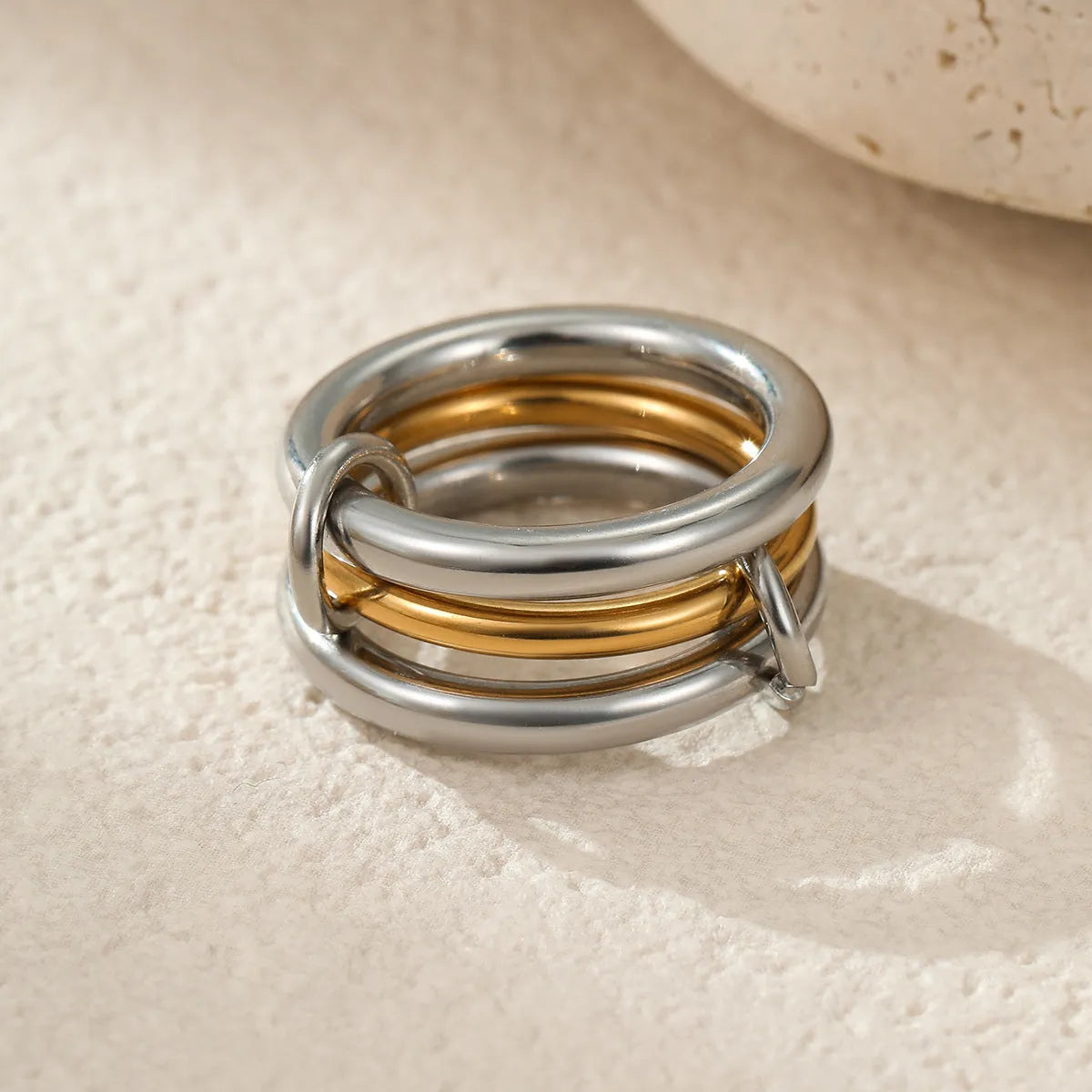 Stacked stainless steel rings with 18K gold plating in exaggerated design on woman's hand