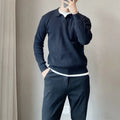 Man wearing a loose black textured knit pullover sweater with long sleeves.