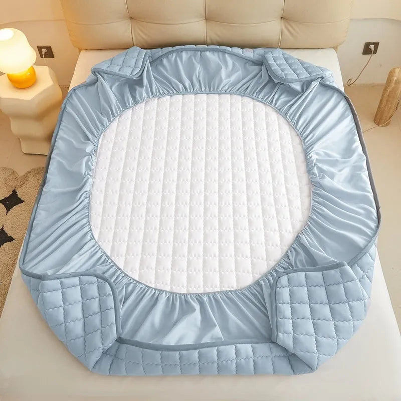 Blue washed cotton waterproof fitted sheet with elasticated edges on mattress.