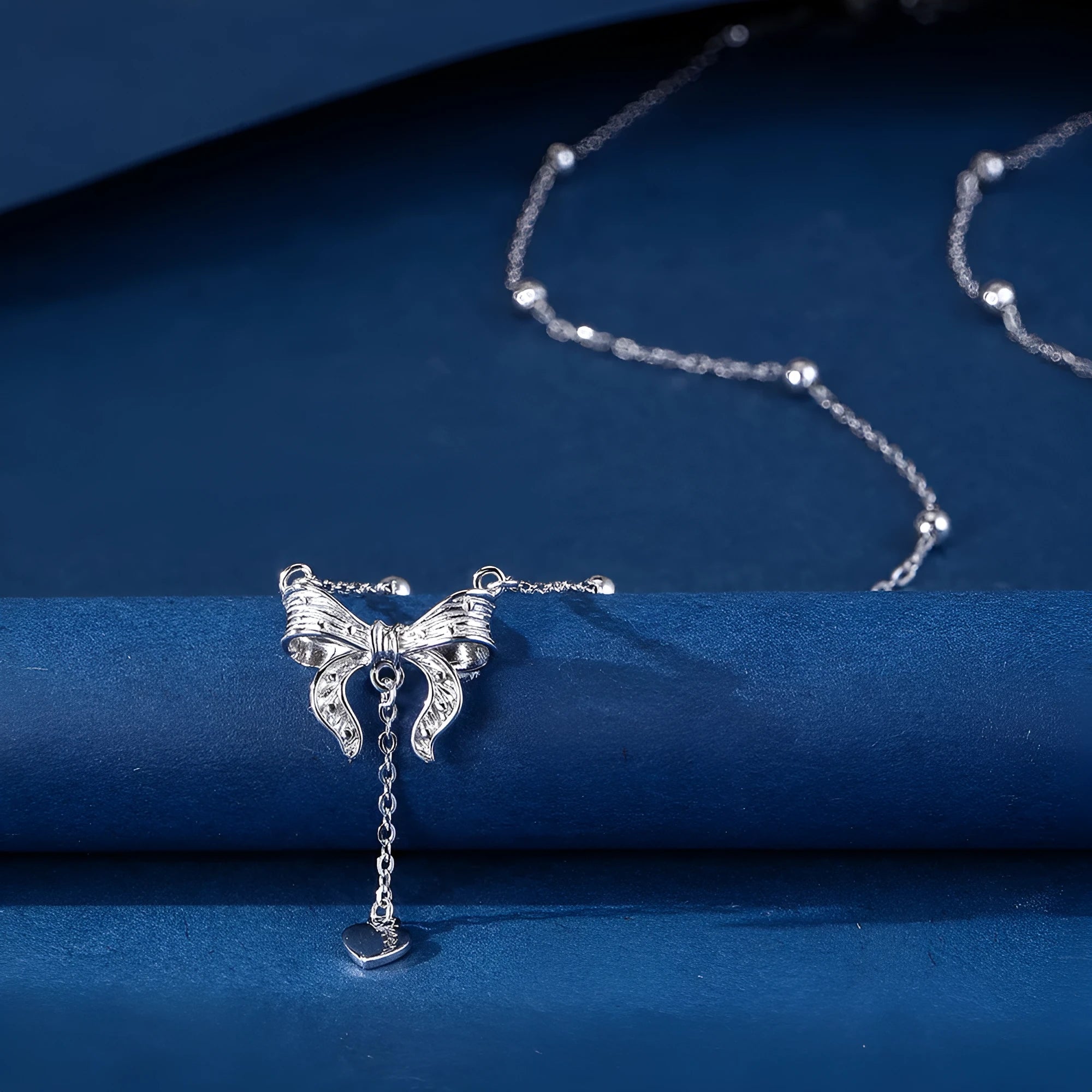 Close-up of a silver heart pendant necklace with butterfly detail on a 40-45cm O-ring chain.