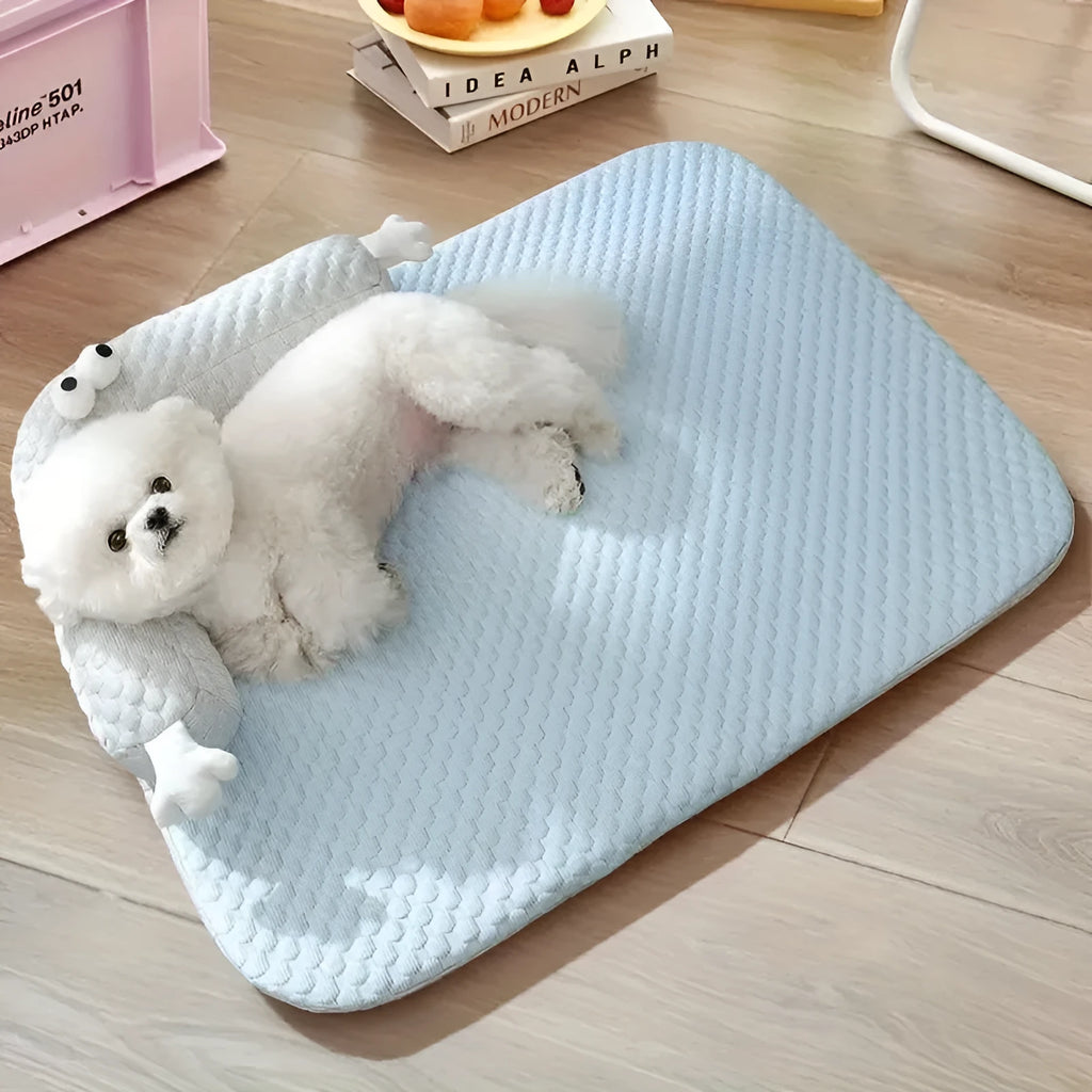 Blue pet bed with big-eyed monster design on a wooden floor next to a cat.