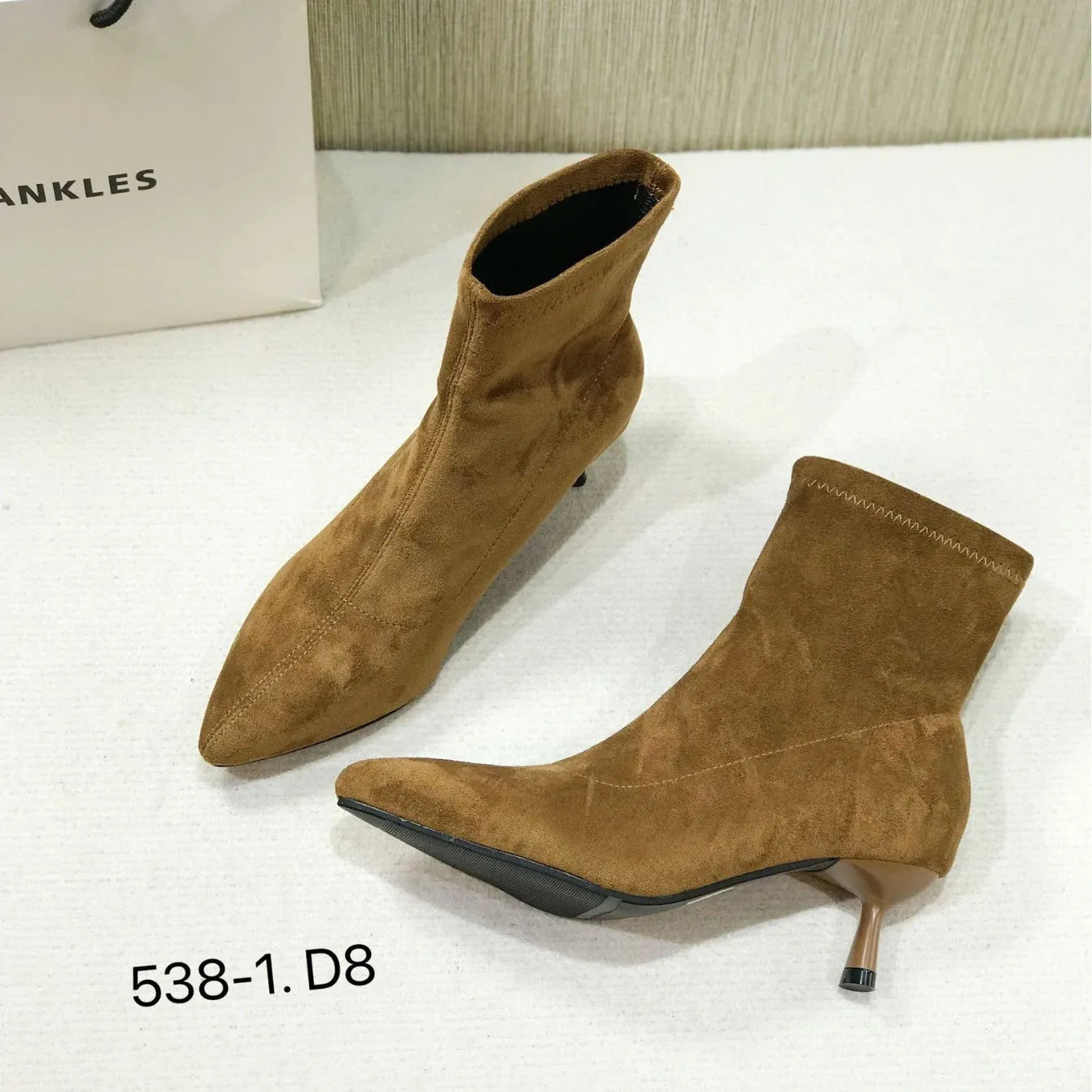 Black pointed toe stiletto heel ankle boots with a calf-high shaft on a neutral background.