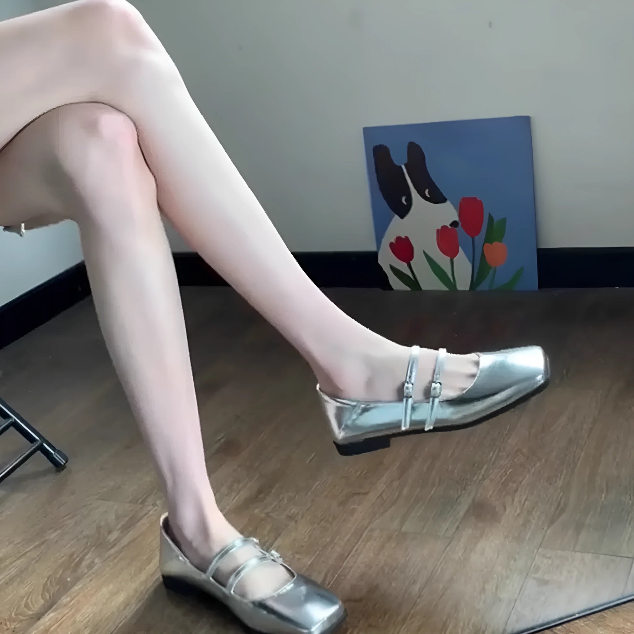 Women's silver leather ballet flats with a cross buckle strap over the instep and a flat sole.