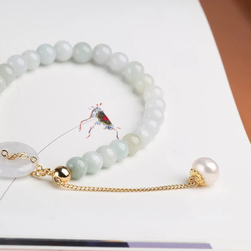 Close-up of a green jade and pearl bracelet with a geometric peace buckle on an elastic band.