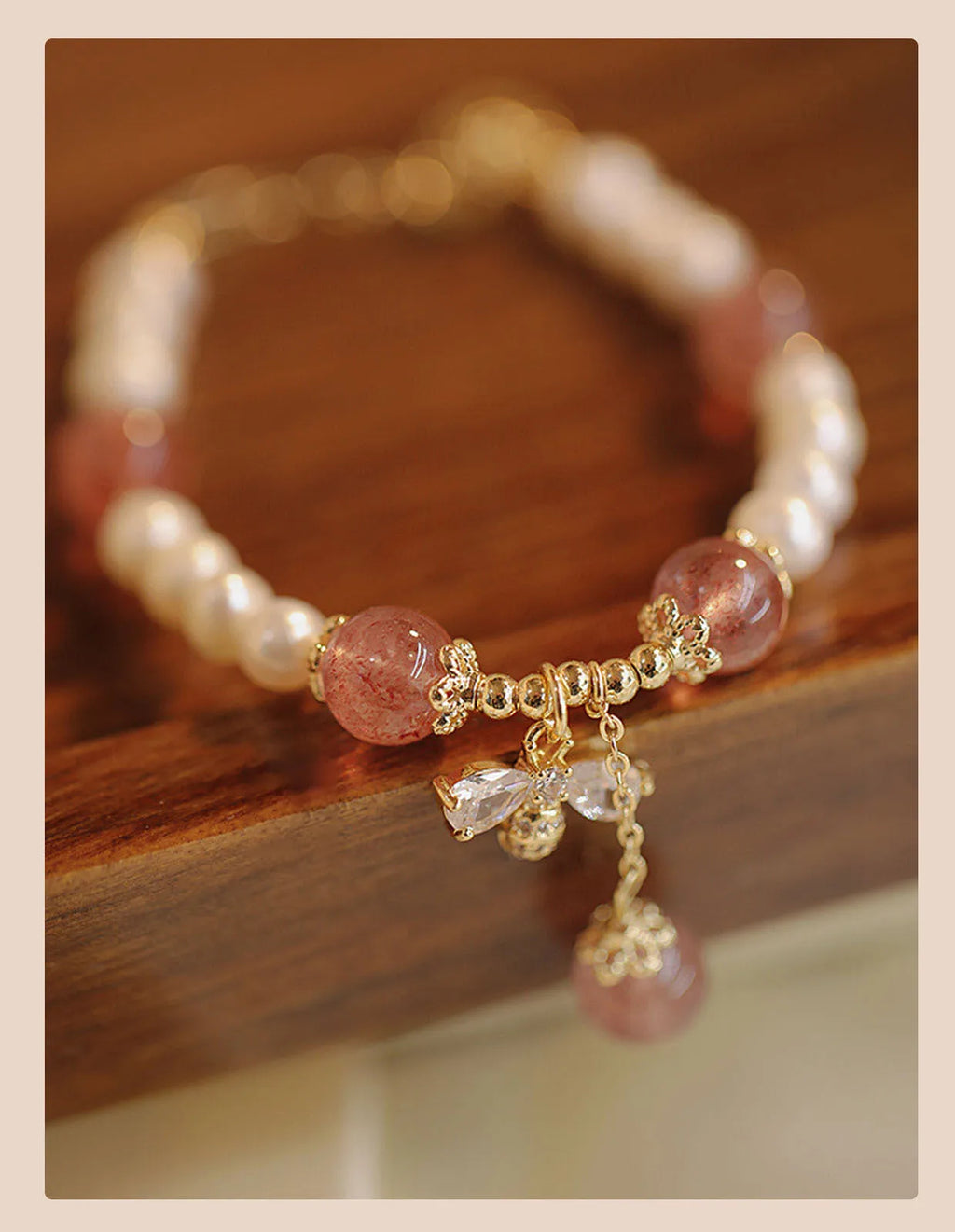 Women's handmade strawberry quartz and crystal bracelet with a decorative bow on a string of beads.