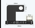 White 4-in-1 foldable wireless charging station showing phone charging on stand, with alarm clock display and RGB night light glow.