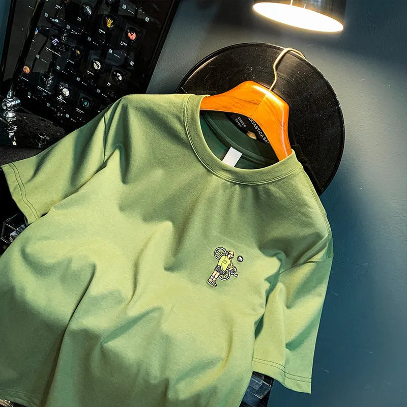Green loose fit men's t-shirt with a front graphic print and short sleeves on a hanger.